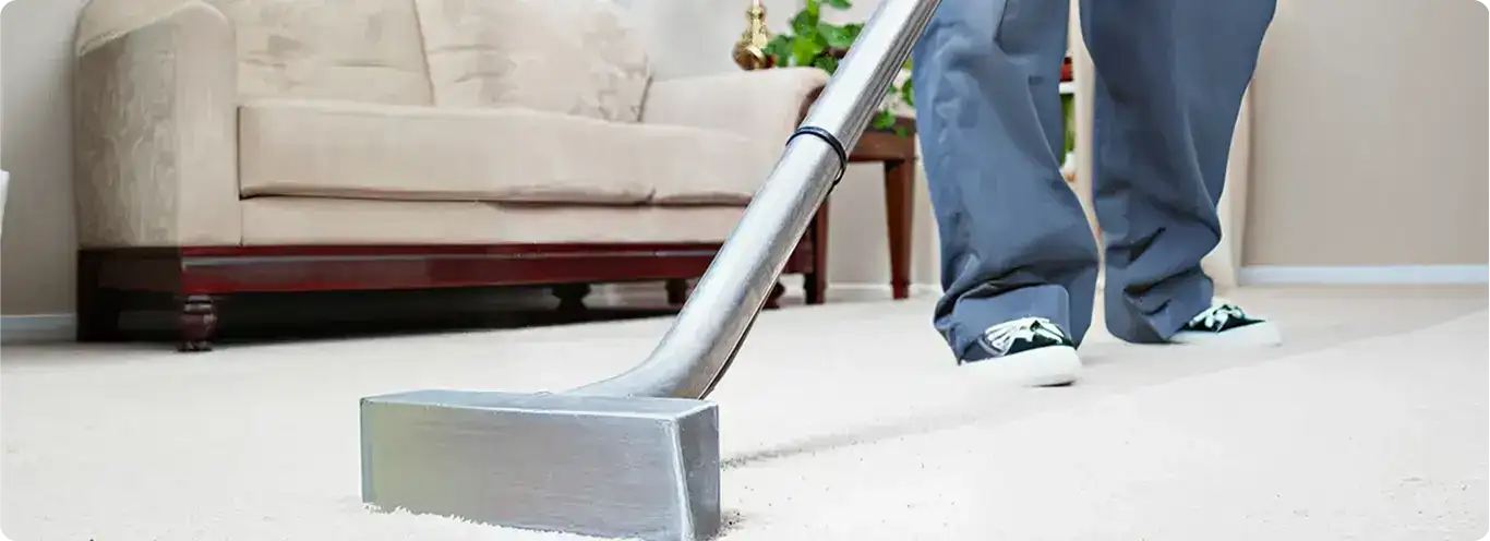 Carpet cleaning technician using a hot-water extraction wand on a light-colored carpet in a living room, Fort Wayne, IN.