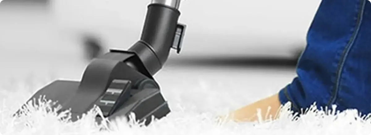 Close-up of a professional vacuuming a white carpet in Ossian.